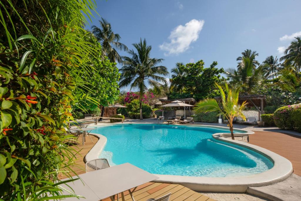 a swimming pool in a resort with palm trees at Zanzibar White Sand Luxury Villas & Spa - Relais & Chateaux in Paje