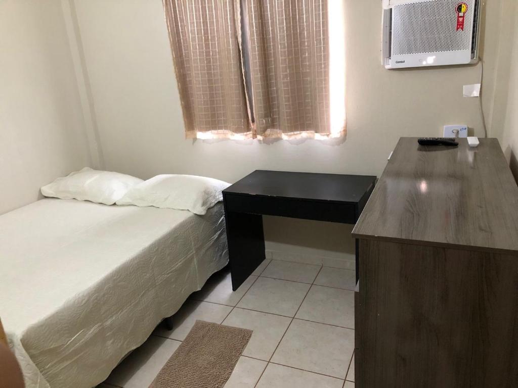 a bedroom with a bed and a desk and a window at Quadra 6 Paiaguás Parque das Águas Cuiabá in Cuiabá
