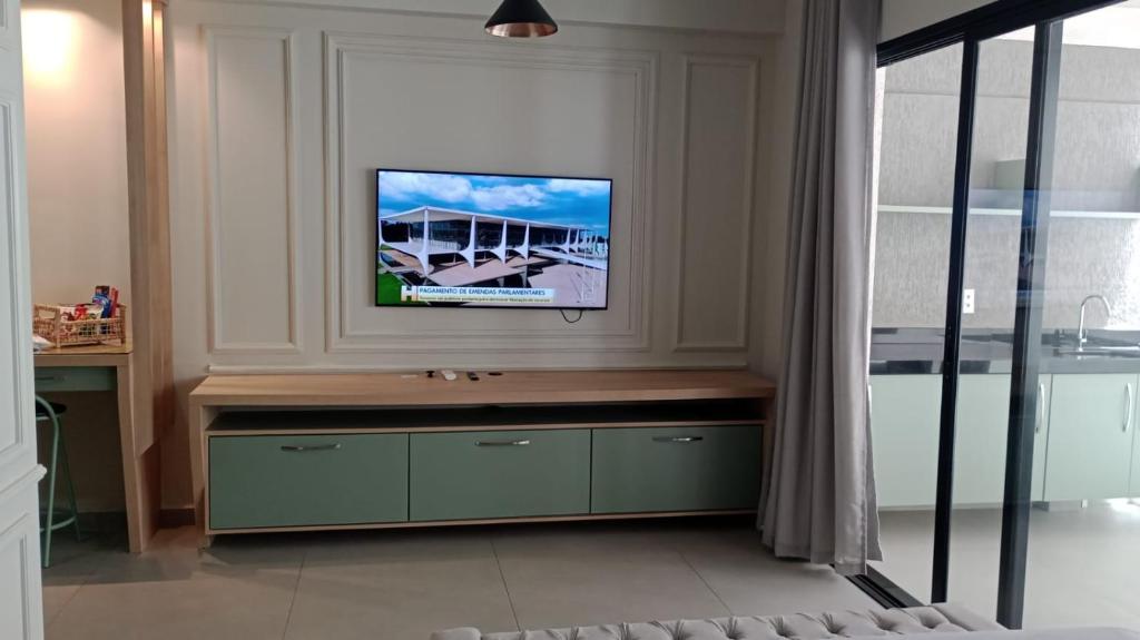 a living room with a flat screen tv on a wall at Studio 709 in Marília