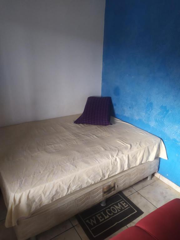 a bed in a room with a blue wall at Lais in Lençóis