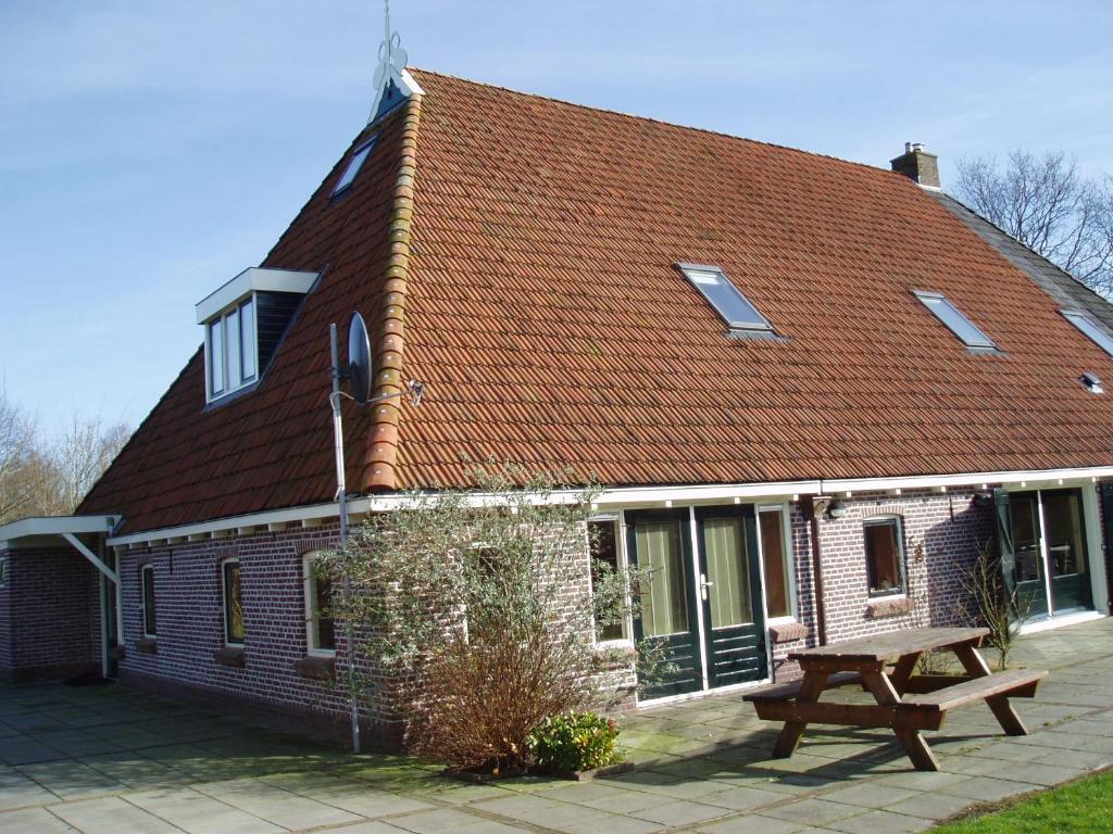 una casa de ladrillo con un banco delante de ella en Logeren bij de Ruimte, en Nijeholtpade