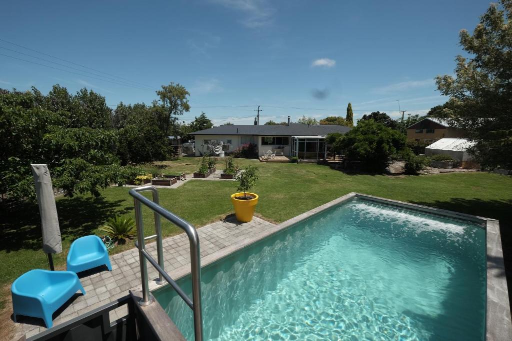 a swimming pool with two blue chairs and a house at Evendale House in Hastings