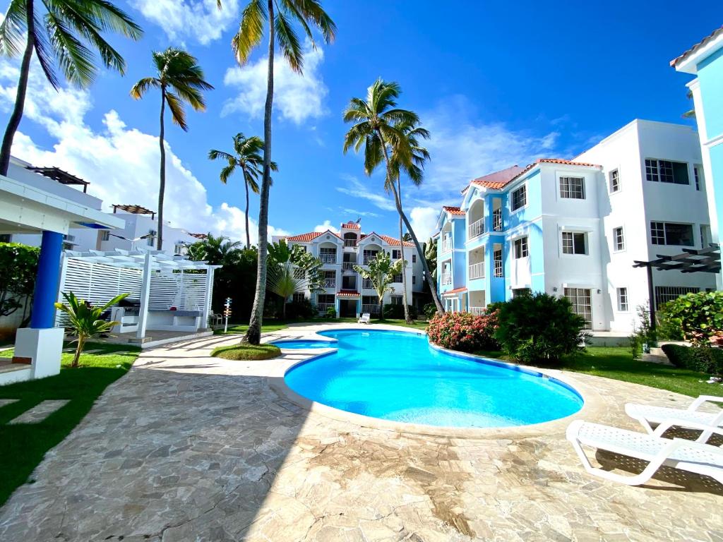 une piscine devant un immeuble avec des palmiers dans l'établissement Paradise Arenas De Bávaro RD, à Punta Cana