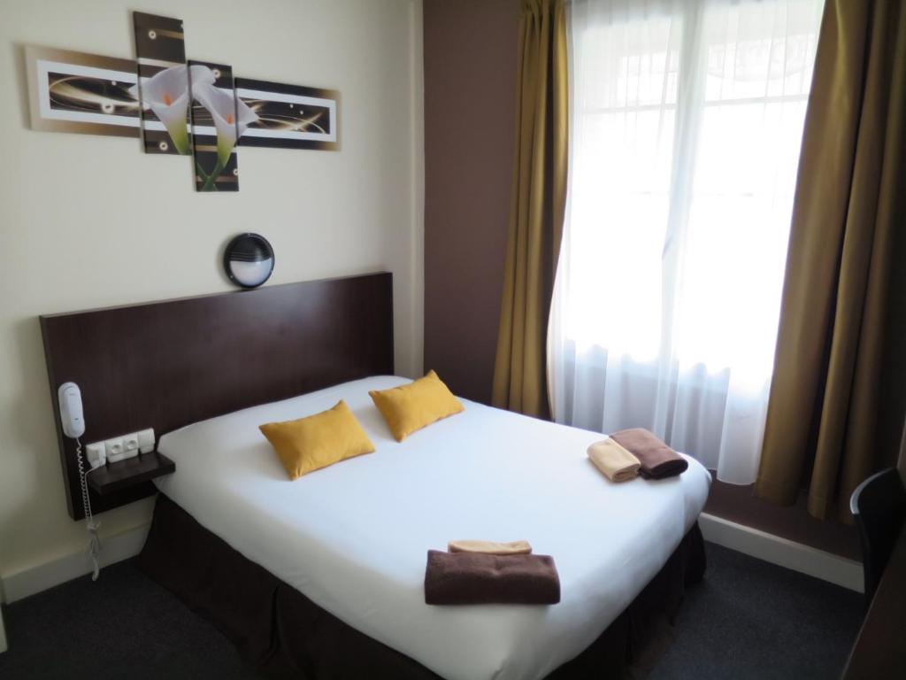 a bedroom with a large white bed and a window at Hotel de la Paix in Caen