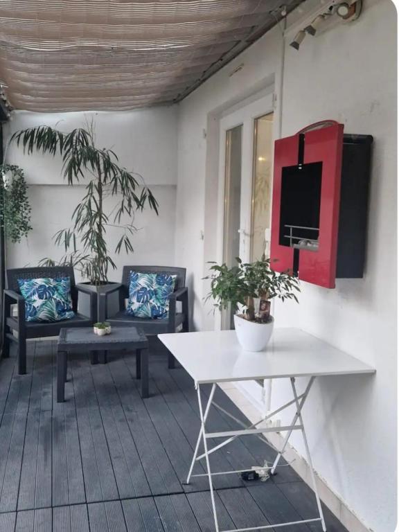 - une terrasse couverte avec 2 chaises et une télévision murale dans l'établissement Villa Elisabeth, à Nice