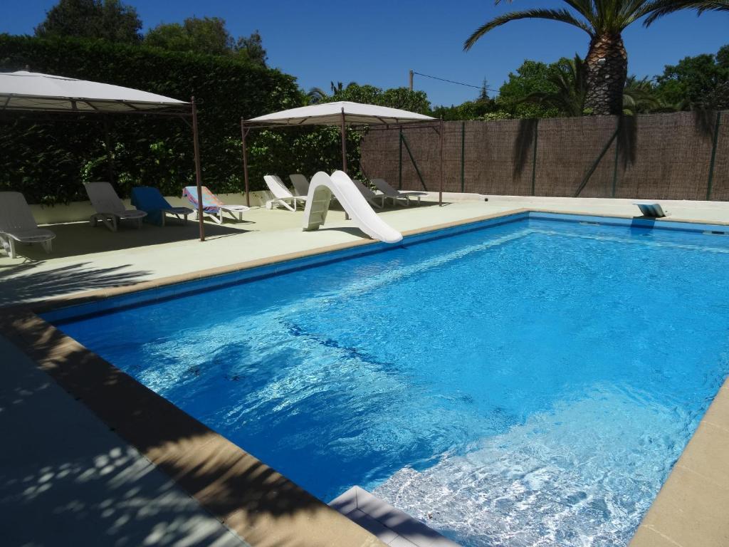 a swimming pool with a slide and some chairs at Le Mas de la Palmeraie - Studio dans propriété privée au calme avec piscine et tennis in Bormes-les-Mimosas