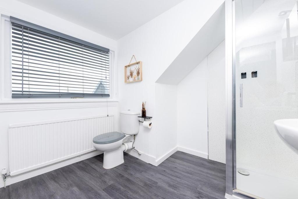 a white bathroom with a toilet and a sink at Ness Heights in Inverness