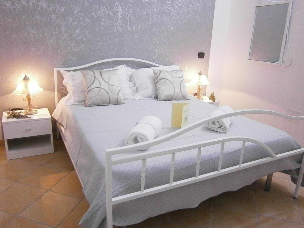 a white bed in a bedroom with two lamps at B&B La Rosa Lampedusa in Lampedusa