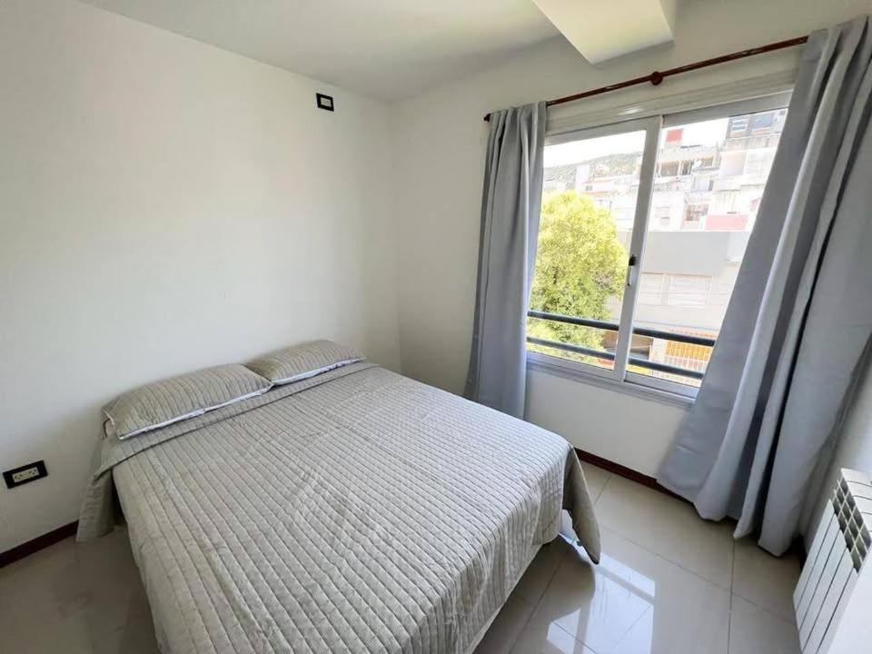 a bedroom with a bed and a large window at Apart San Jose in Villa Carlos Paz