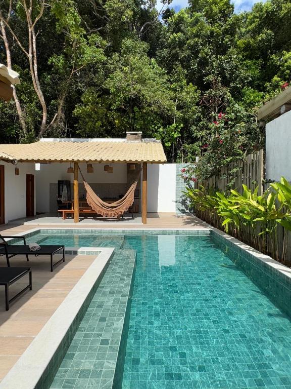 a swimming pool with a hammock next to a house at Casa Encanto de Minas em Trancoso in Trancoso