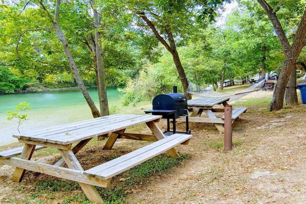 a group of picnic tables next to a river at Treehouse 1 Mockingbird Lodge in New Braunfels