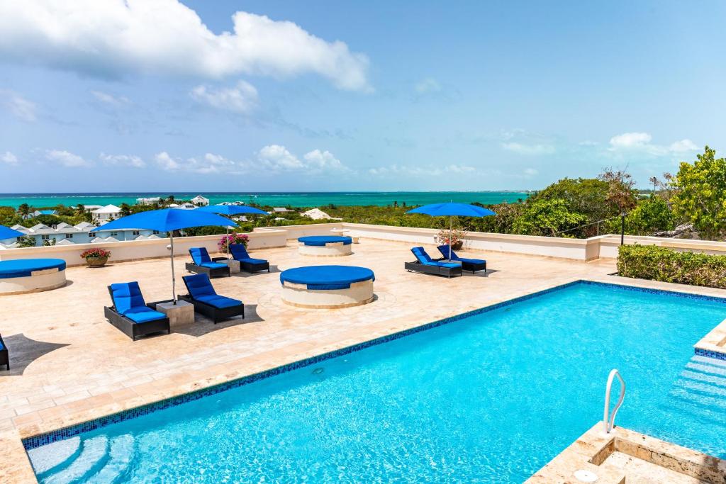 ein Swimmingpool mit Liegen und Sonnenschirmen und das Meer in der Unterkunft Hidden Haven III - Cozy For Couples in The Bight Settlements