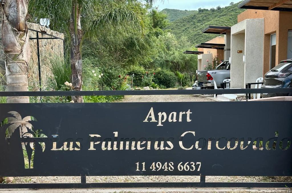 ein Schild vor einem Haus mit einem Gebäude in der Unterkunft Apart Las Palmeras Corcovado in Villa Rumipal