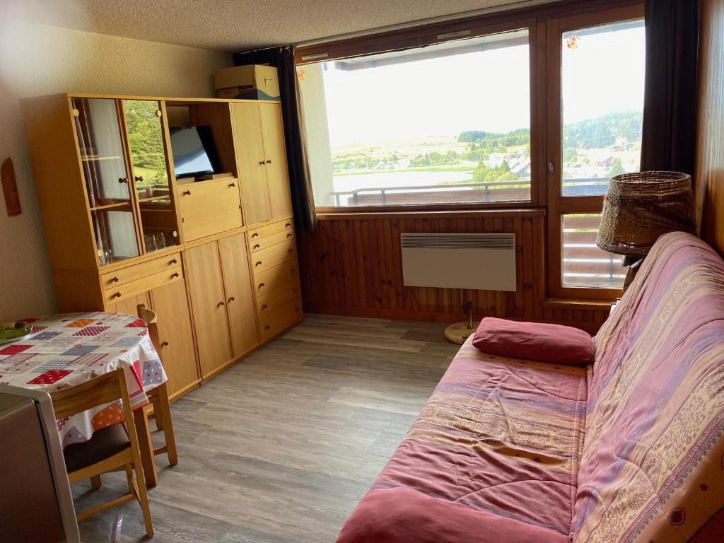 Cette chambre comprend un lit et une grande fenêtre. dans l'établissement Studio au centre station avec balcon et parking gratuit - FR-1-814-12, à Besse-et-Saint-Anastaise