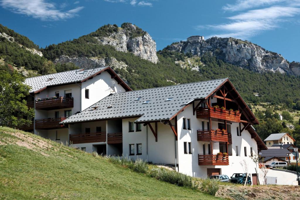 um edifício numa colina com montanhas ao fundo em Résidence Plein Soleil em Avrieux