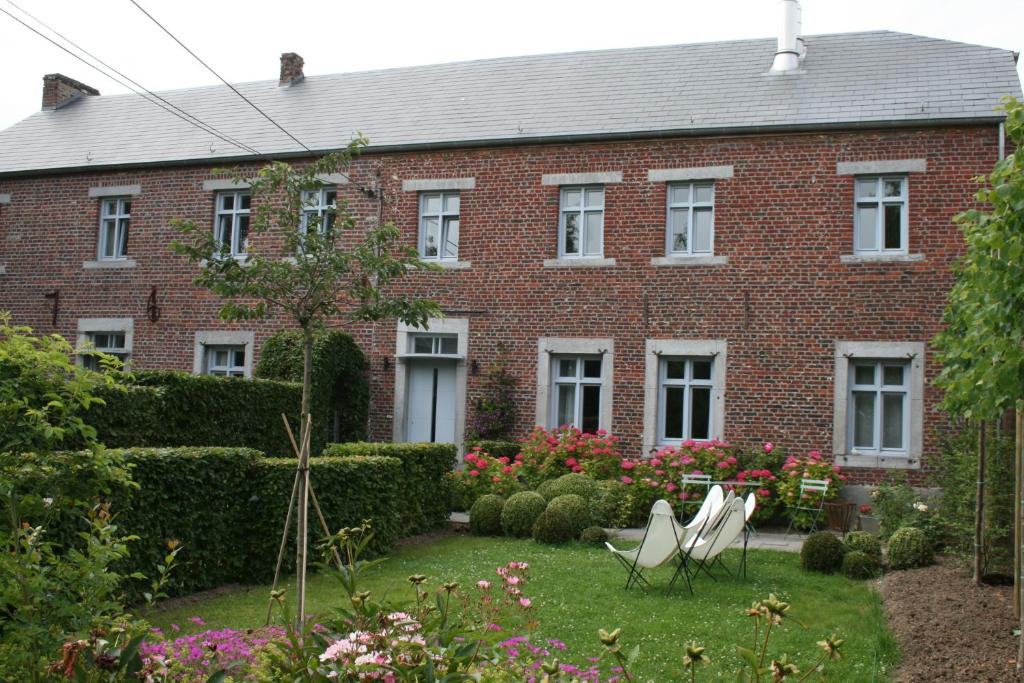 ein rotes Backsteinhaus mit zwei weißen Stühlen im Hof in der Unterkunft B&B La Chambre d'à Côté in Aische-en-Refail