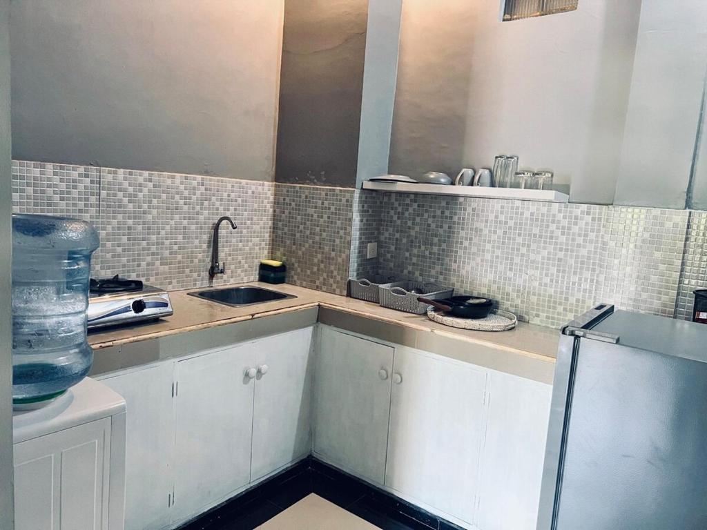 a kitchen with white cabinets and a sink and tiles at Gladstudio in Kerobokan