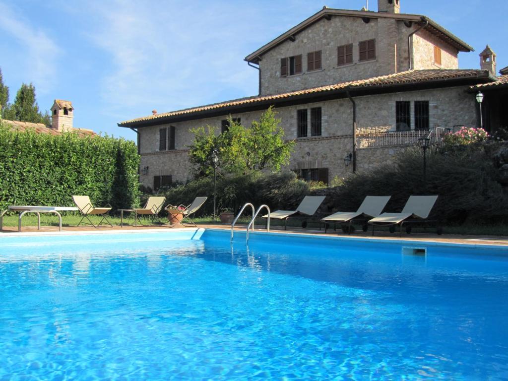 een groot zwembad met stoelen en een huis bij Casale Dolci Dimore in Massa Martana
