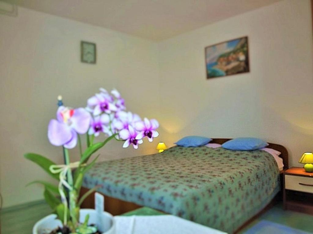 a bedroom with a bed and a vase with purple flowers at Apartment Koric in Ičići