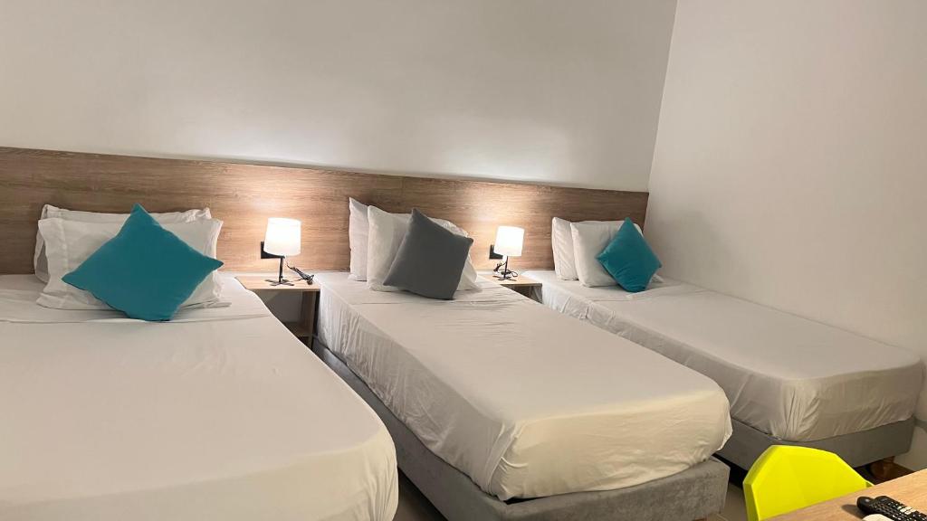 a room with three beds with blue pillows at HOTEL 9.5 SAN FERNANDO in Cali