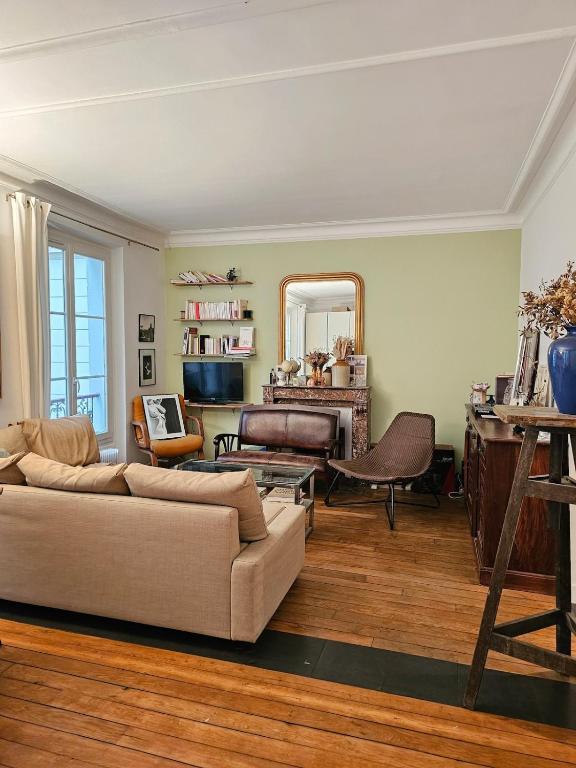 un salon avec un canapé et un miroir dans l'établissement Buttes Chaumont apartement, à Paris