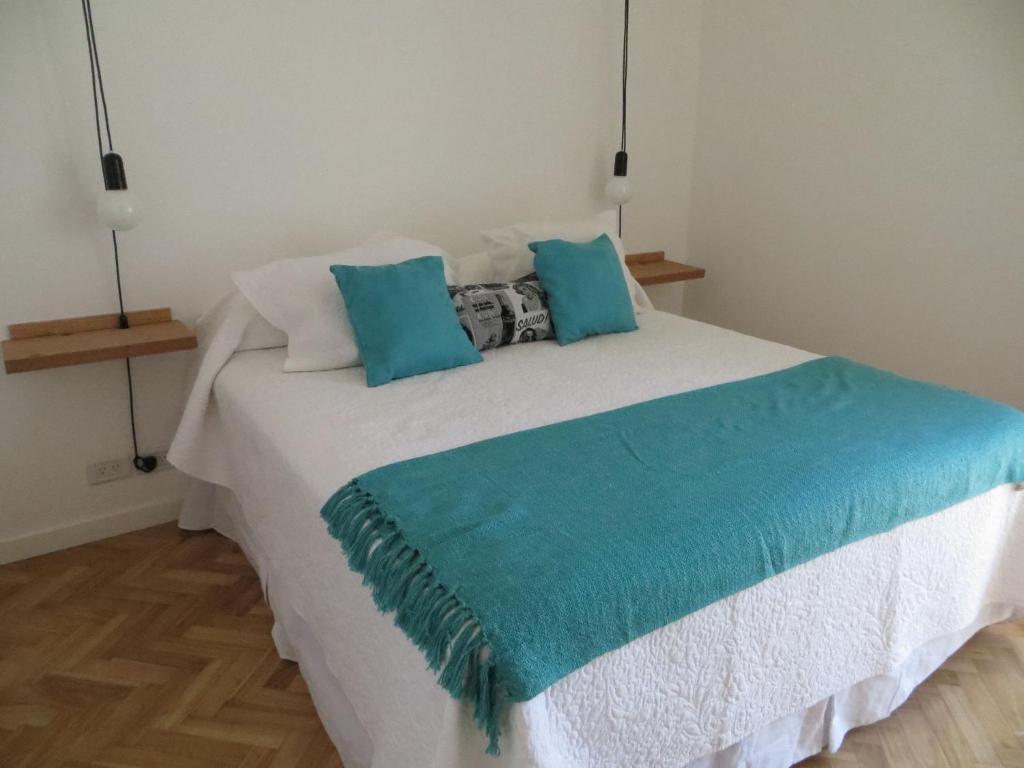 1 dormitorio con 1 cama blanca grande con almohadas azules en Sunny Recoleta Apartment en Buenos Aires