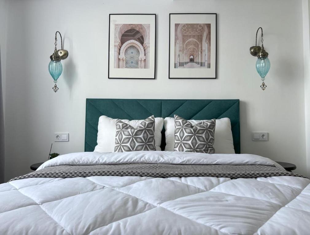 Un dormitorio con una cama grande con dos cuadros en la pared. en Eastern style apartment in Golden Square!, en Almaty