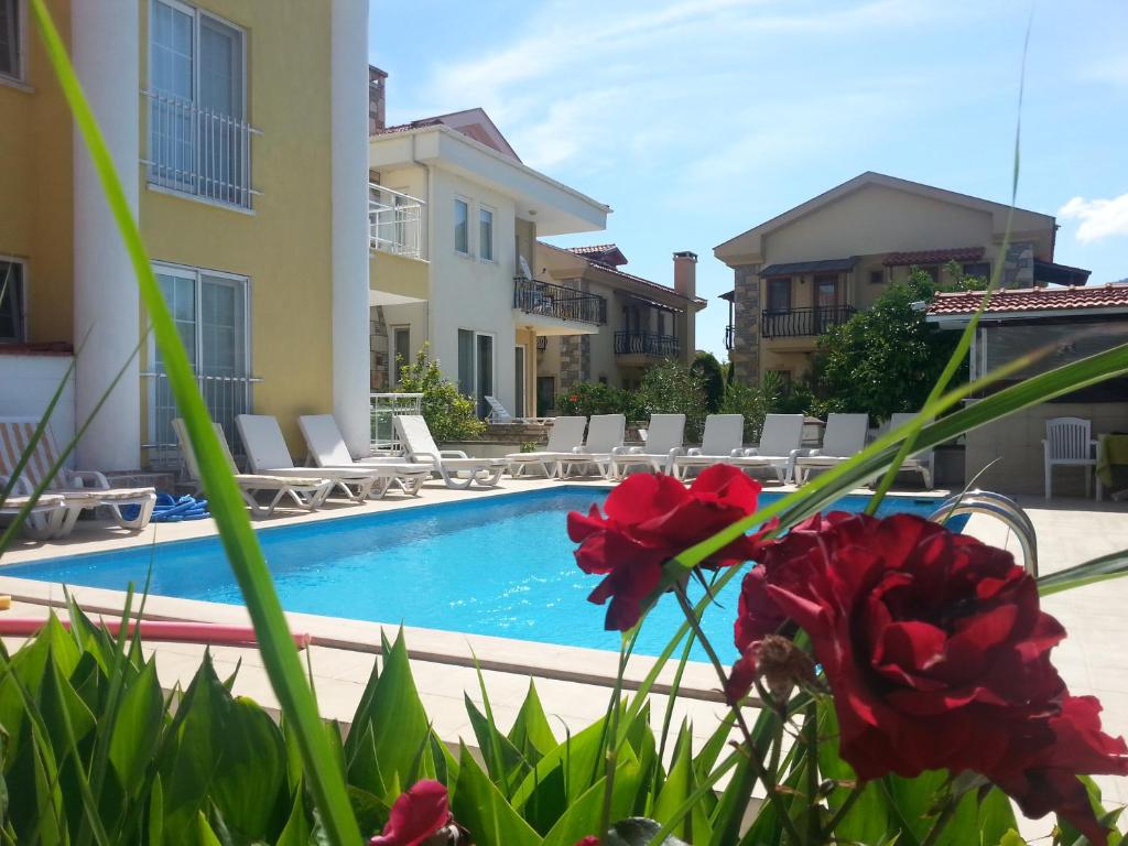 a villa with a swimming pool and red flowers at Karaca Apart Hotel in Dalyan