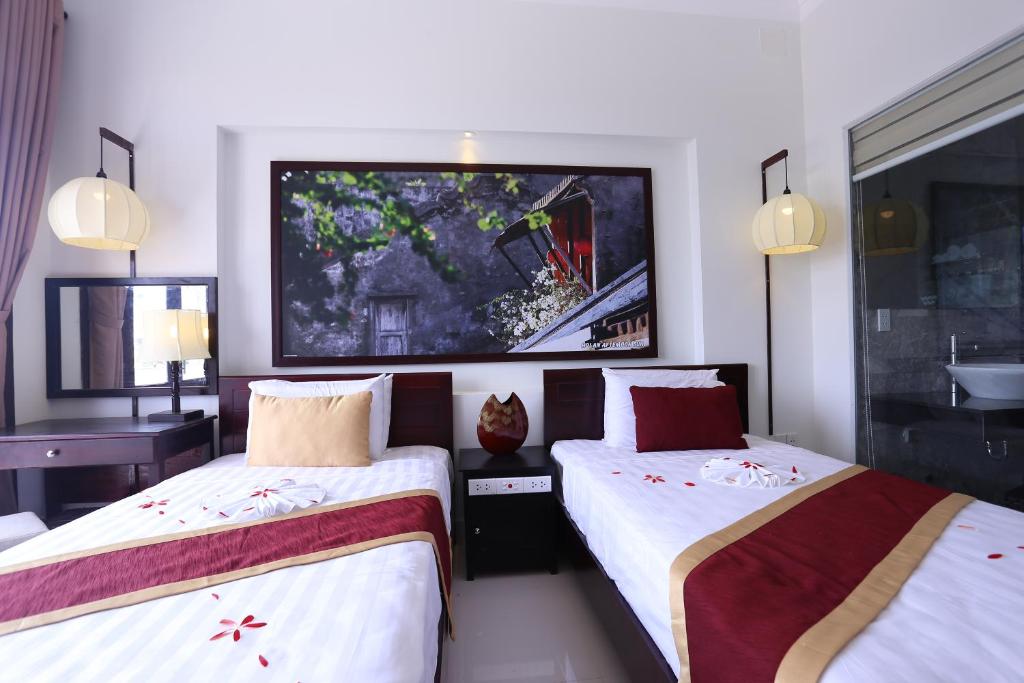 a hotel room with two beds and a tv on the wall at The House 36 in Hoi An