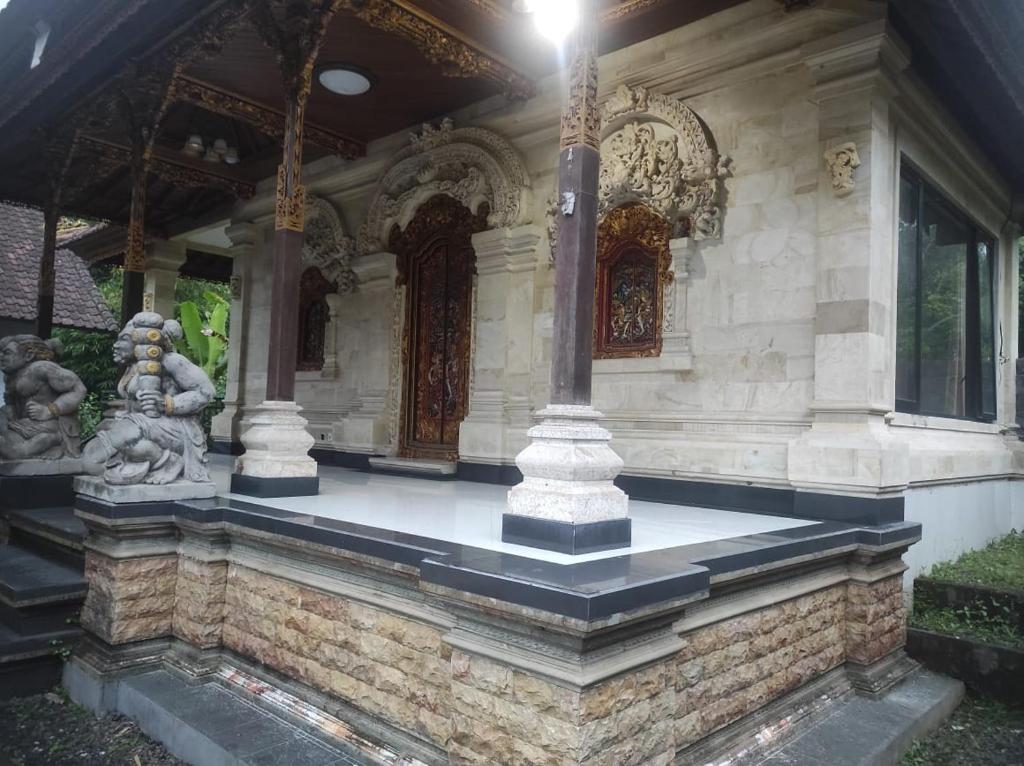 a building with a statue on the front of it at Men Sari Homestay in Tabanan