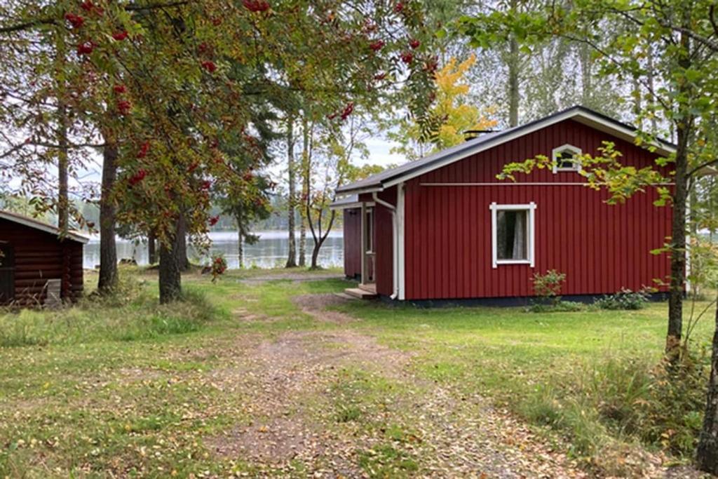 a red cabin with a yard next to a lake at Vuonamo - Summer cottage in Keitele