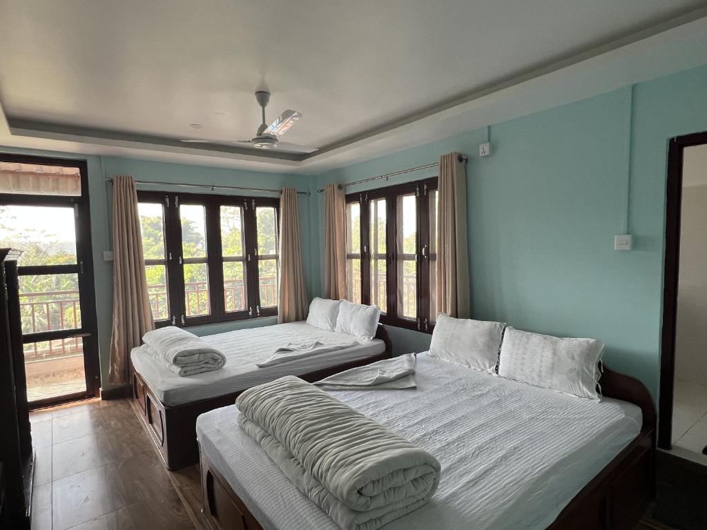 索拉哈Sauraha Guest House的带窗户和床罩的客房内的两张床