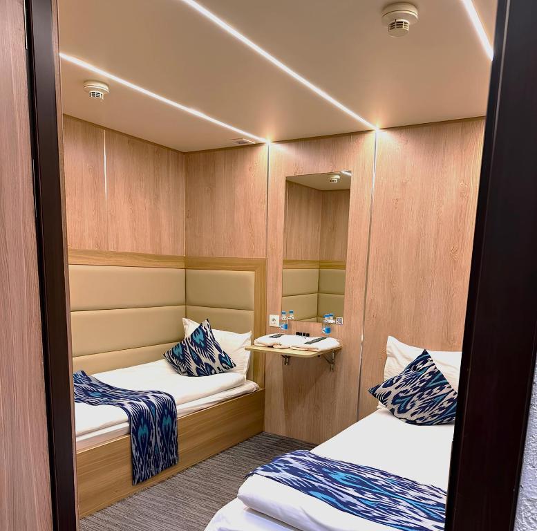 a small room with two beds and a mirror at Qo'noq Tashkent Airport Hotel Sleep Lounge & Showers, Terminal 2 - TRANSIT ONLY in Tashkent