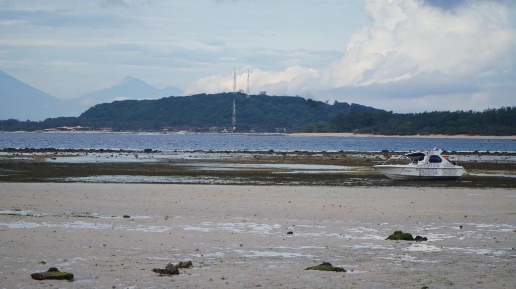a boat sitting on the shore of a beach at Mola2 Resort Gili Air in Gili Islands