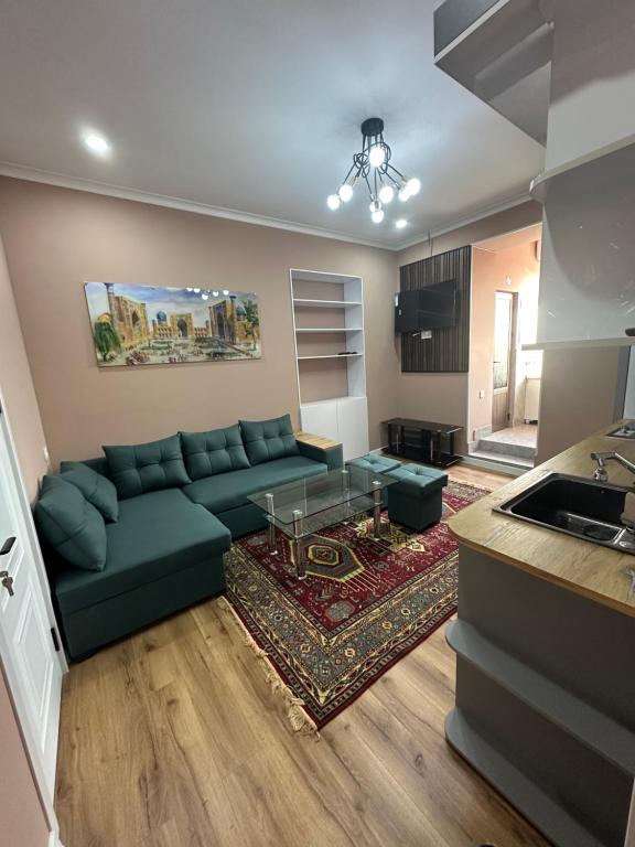 ein Wohnzimmer mit einer grünen Couch und einer Küche in der Unterkunft Apartments with Registan view in Samarkand