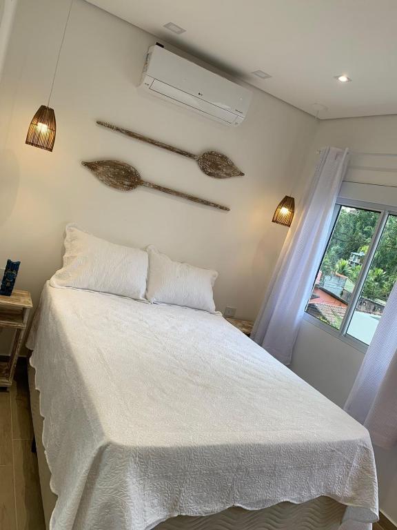a bedroom with a white bed and a window at Casa da Tieko - Suítes no Perequê in Ilhabela