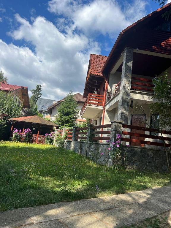 a house with a fence next to a yard at RED HOUSE Sinaia in Sinaia
