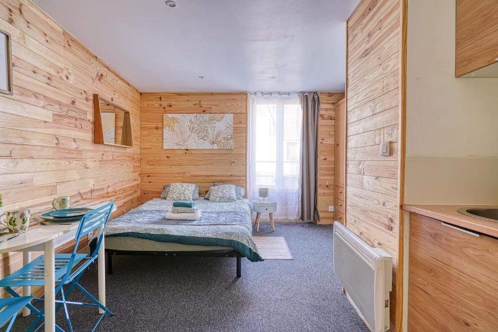 une chambre avec un lit dans une pièce aux murs en bois dans l'établissement Studio Himalaya-Au coeur de la ville, à Palaiseau