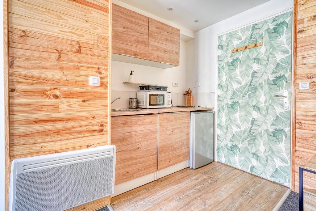 a kitchen with wood paneled walls and a refrigerator at Studio Himalaya Rénové et lumineux in Palaiseau