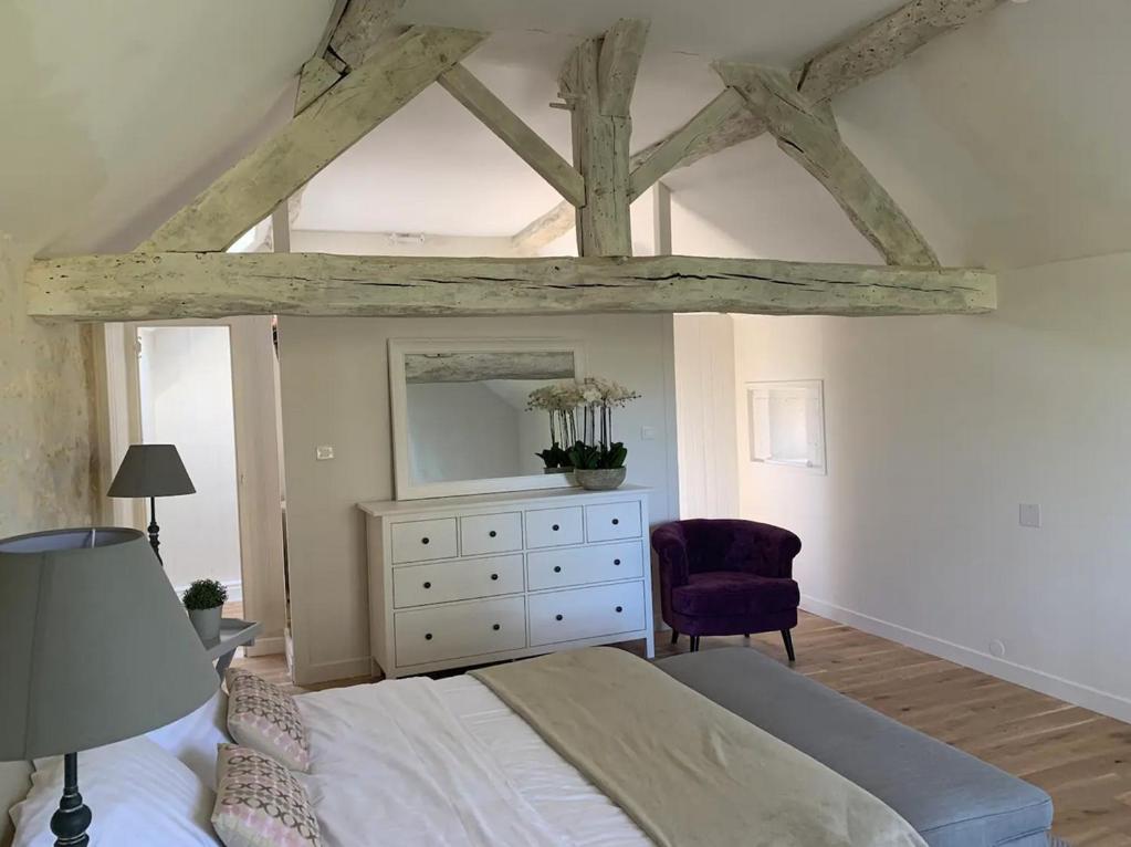 a bedroom with a bed and a dresser with a mirror at Le Cottage Lascaux in Bourrou