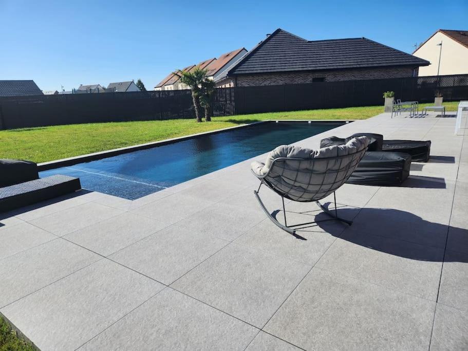 une chaise assise sur une terrasse à côté d'une piscine dans l'établissement Villa Maison 5 chambres, à Vitry-en-Artois