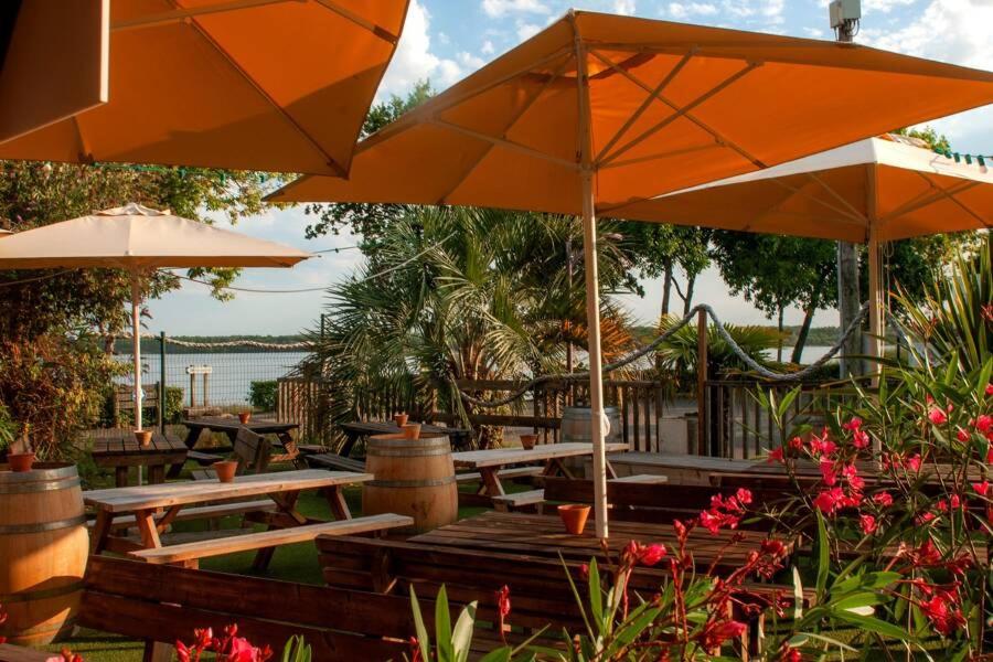 une terrasse avec des tables et des parasols ainsi qu'une aire de jeux dans l'établissement Le rivage des Landes, à Aureilhan