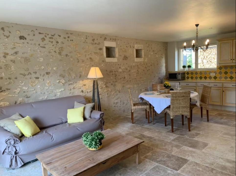 ein Wohnzimmer mit einem lila Sofa und einem Tisch in der Unterkunft Le Cottage Rouffignac in Bourrou