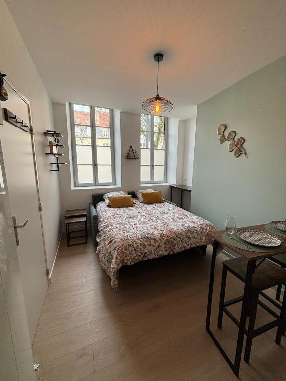 une chambre avec un lit, une table et des fenêtres dans l'établissement Studio Le Moulinois, à Moulins