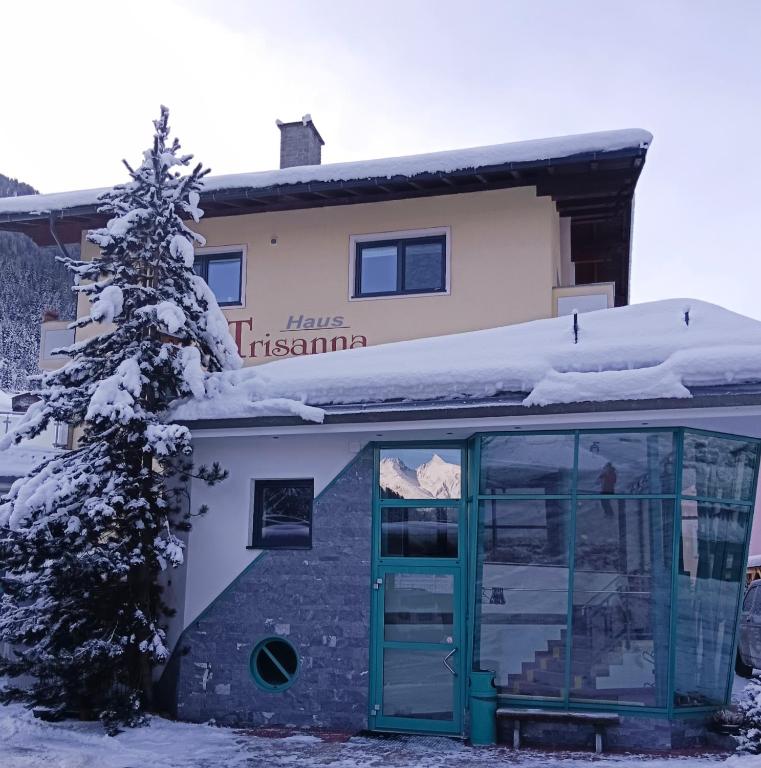 a building with a green door in the snow at Apart Trisanna in Kappl