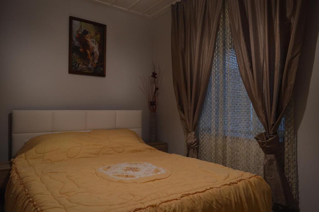 a bedroom with a bed and a window with curtains at Стаи за гости VIVIA in Veliko Tŭrnovo