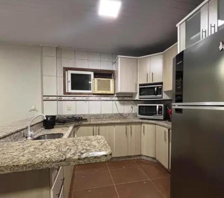 a kitchen with white cabinets and a stainless steel refrigerator at Beleza pura in Santa Rosa