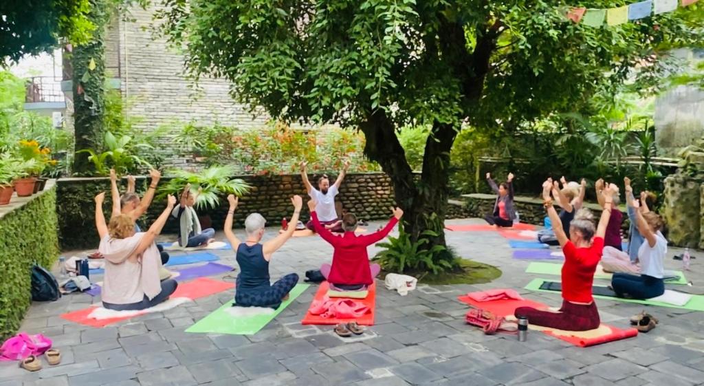 un gruppo di persone in una lezione di yoga sotto un albero di Mum's Garden Resort a Pokhara