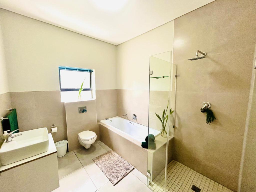 a bathroom with a toilet and a tub and a sink at Sakkie se Dakkie in Agulhas