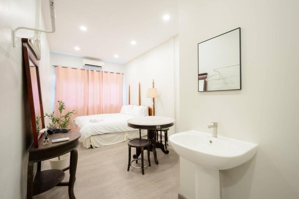a white bathroom with a sink and a bed at CASA Yaowarat Road ถนนเยาวราช in Samphanthawong